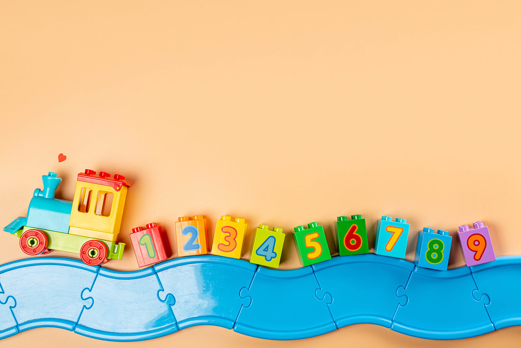Train with numbers on multicolored parts of the constructor, orange background and blue road Train with numbers on multicolored parts of the constructor, orange background and blue road